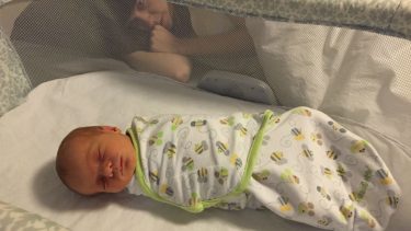 Baby sleeping in crib, mom staring in the back at baby