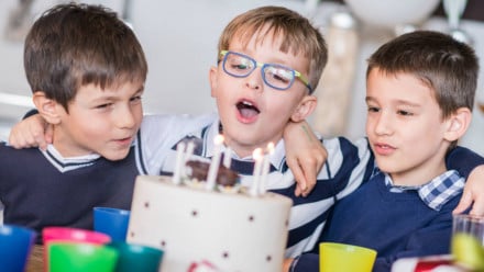 Three boys with a birthday cake at a birthday party
