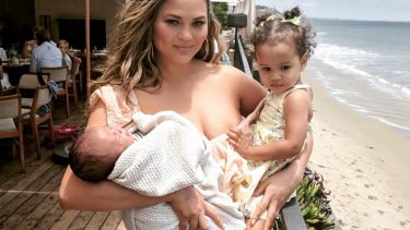 Chrissy Teigen posing with baby Miles and toddler Luna in her arms