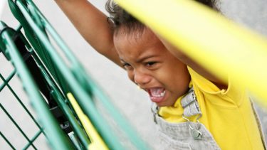 Child crying, hanging off shopping cart
