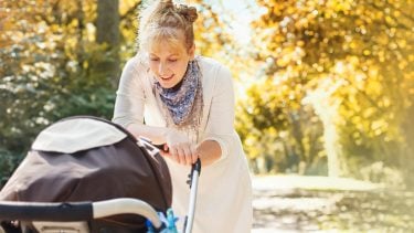 woman looking at her baby in a stroller while on a walk