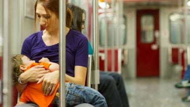 mother breastfeeding her toddler on the subway