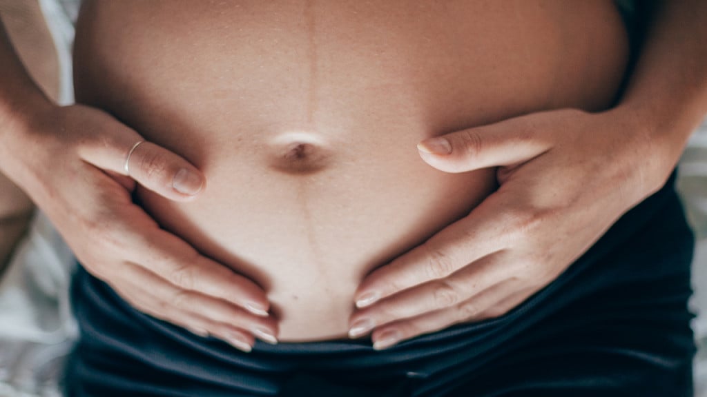 A pregnant woman holding her belly and feeling the baby move