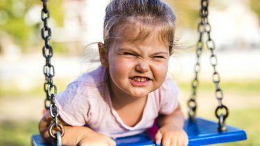 Cute little girl on swing making funny face
