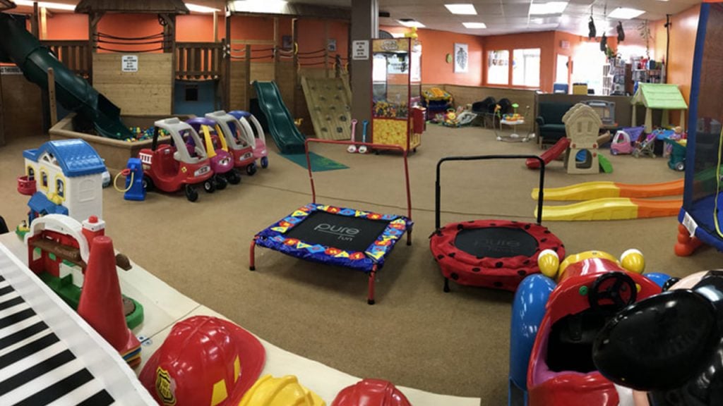 indoor play area with a play structure, trampolines, slides and various toys