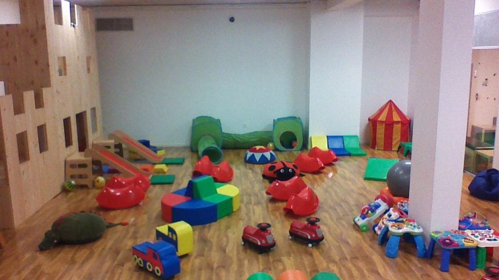 Play room with a wooden castle structure and toys scattered on the floor