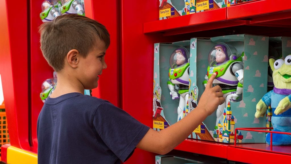 Kid looking at a Buzz Lightyear toy on a store shelf
