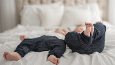 Twins lying on the bed playing