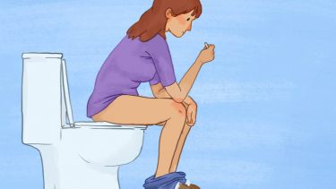 A woman sitting on the toilet looking at an ovulation test