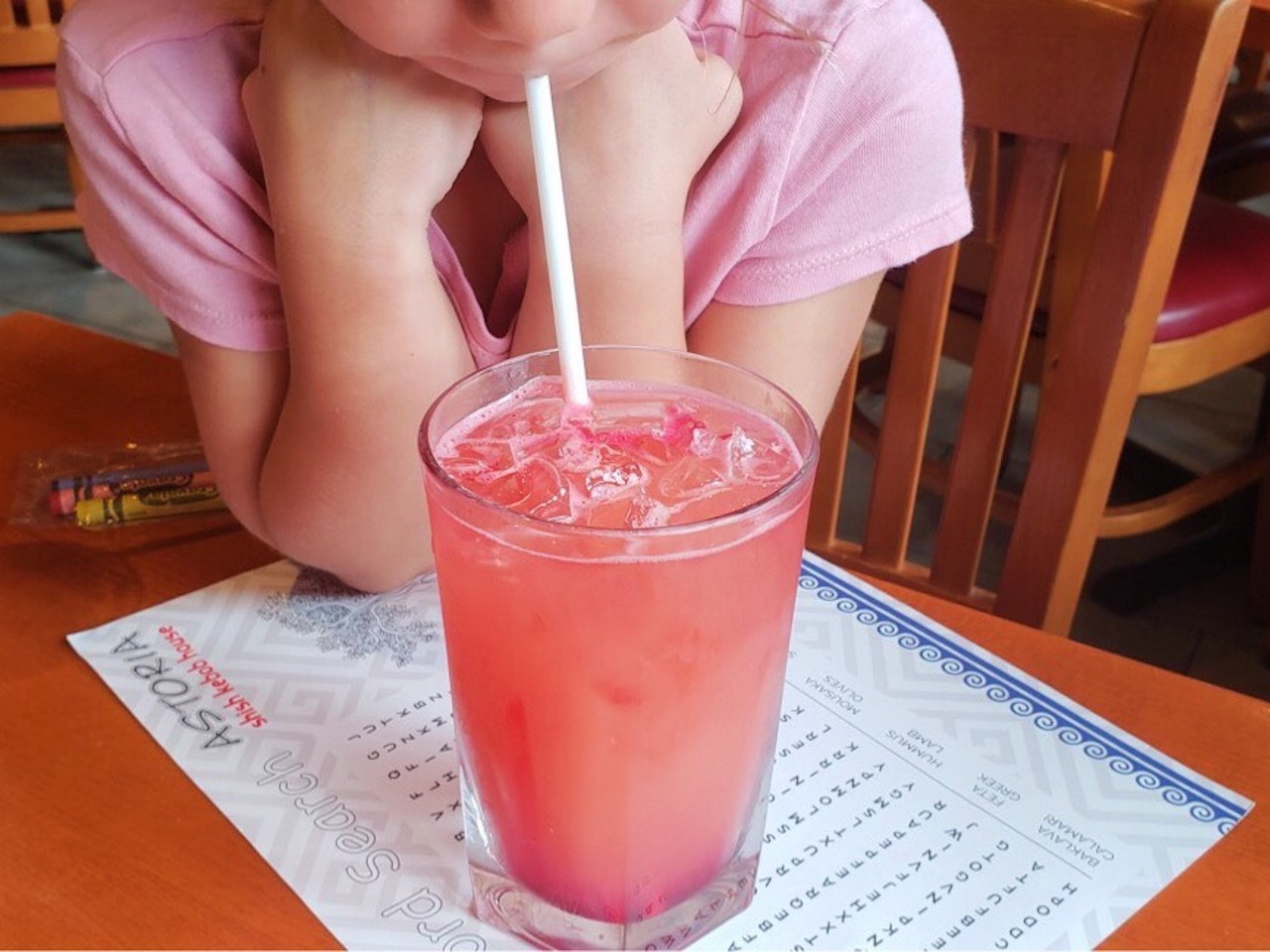 Kid drinking a pink beverage with a straw
