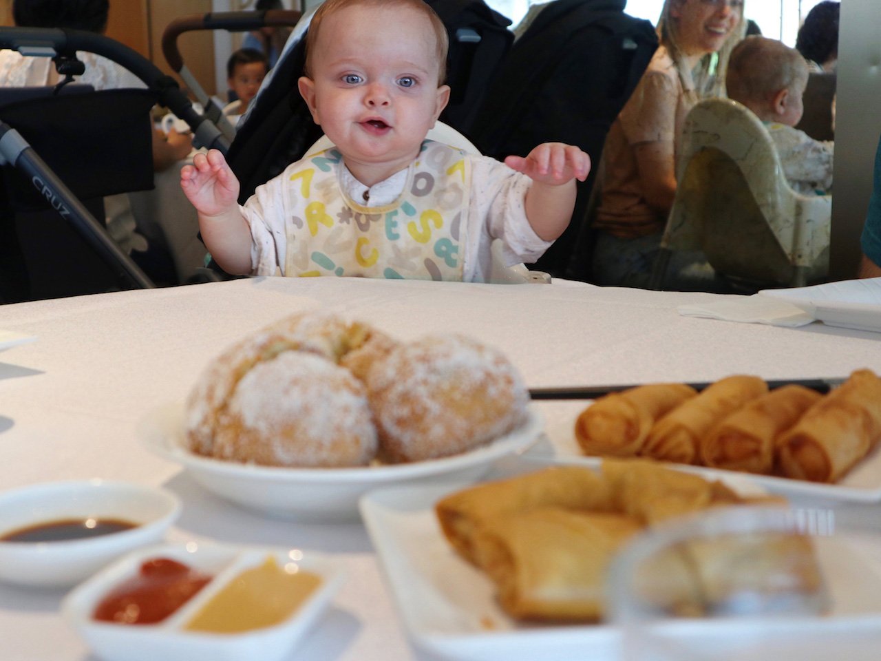 baby looking across table at plates of food