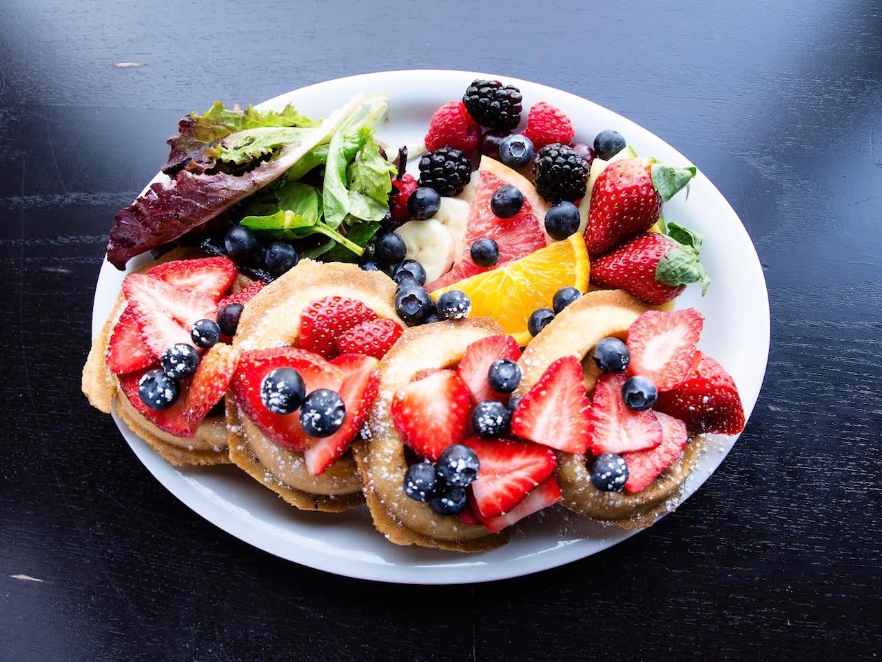 plate of pancakes covered in strawberries and blueberries.
