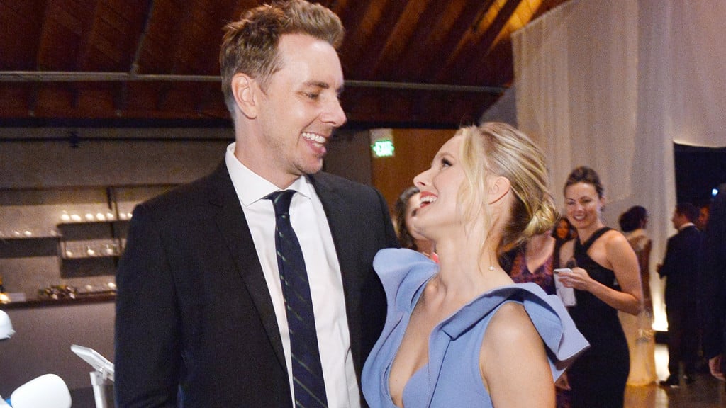 Kristen Bell and Dax Shepard looking at each other and laughing on a red carpet