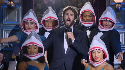 Josh Groban singing surrounded by dancers wearing shark heads