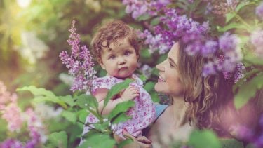 Mom holding baby girl while surrounded by purple flowers