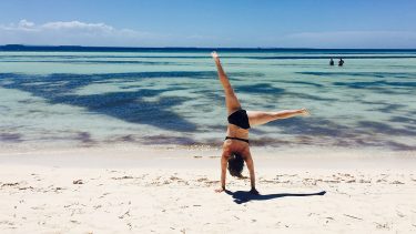 woman doing cartwheel on beach