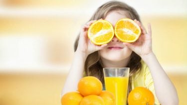 A girl holds oranges in front of her eyes