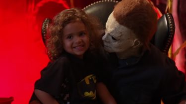 Little girl smiles while taking a Santa photo with Michael Myers from the Halloween movies
