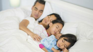 Family of four sleeping in bed together