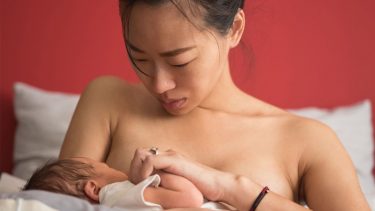 A woman holding her newborn in bed.