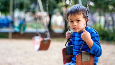 kid on swings looking somber