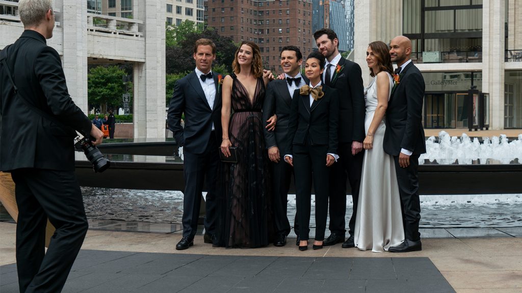 Promo image for Friends From College showing a group of friends taking a picture near a fountain wearing formalwear