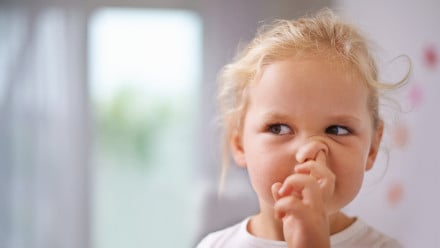 little girl with finger up her nose