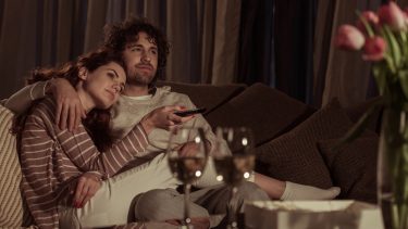 couple on couch watching tv drinking wine