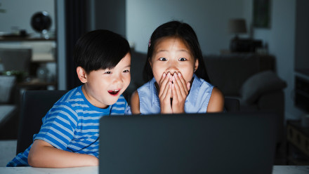 2 kids looking at laptop shocked