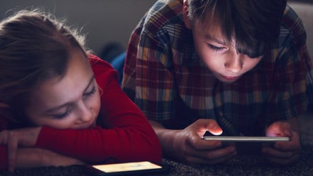 2 kids on devices in dark