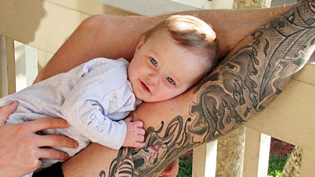 Baby daughter laying on Kevin's tattooed leg