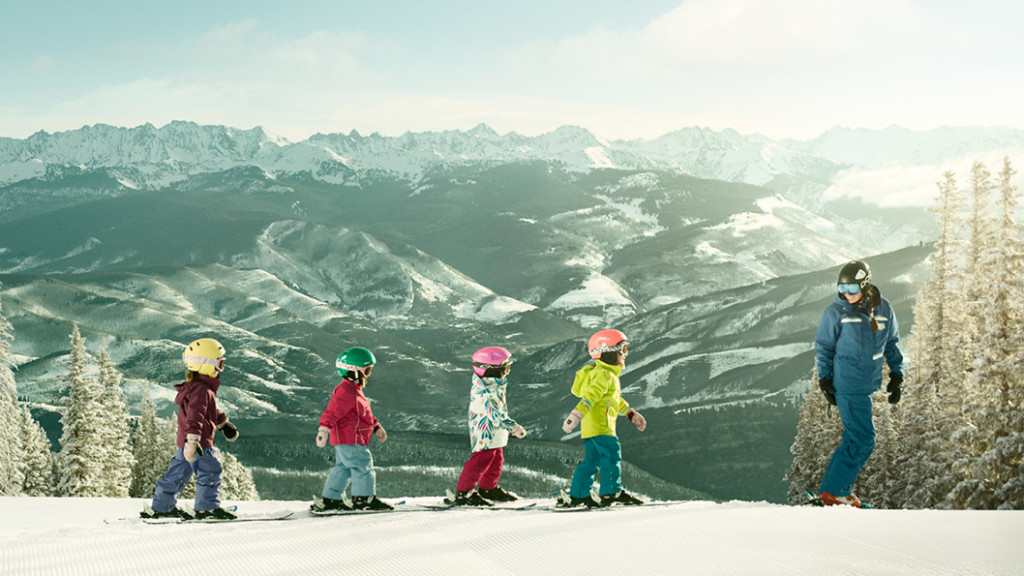 kids skiing in a row at top of mountain