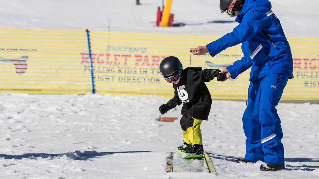 small child learning to snowboard
