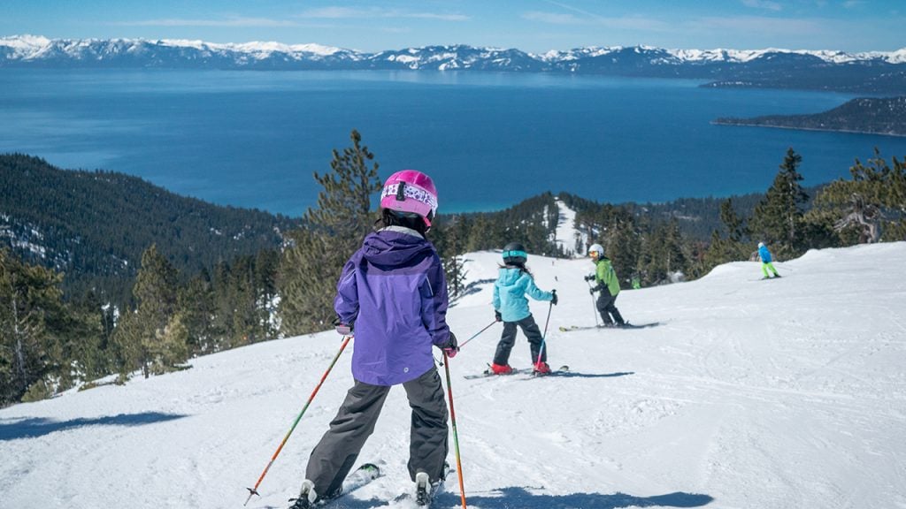 kids skiing down mountain with view of Lake Tahoe