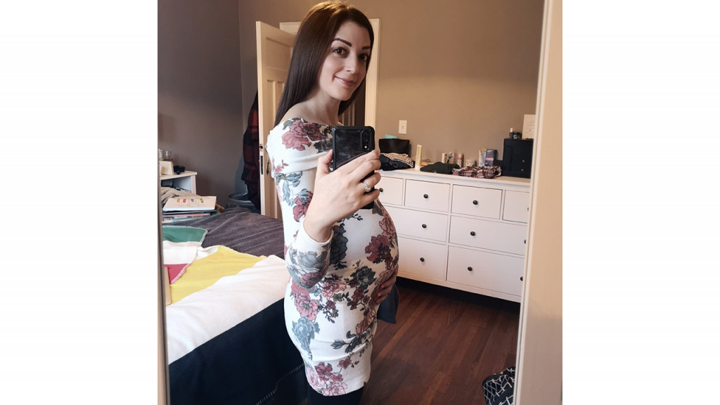 Women taking a mirror selfie of her pregnant belly