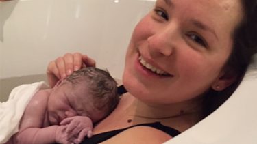 Mother holding newborn in tub