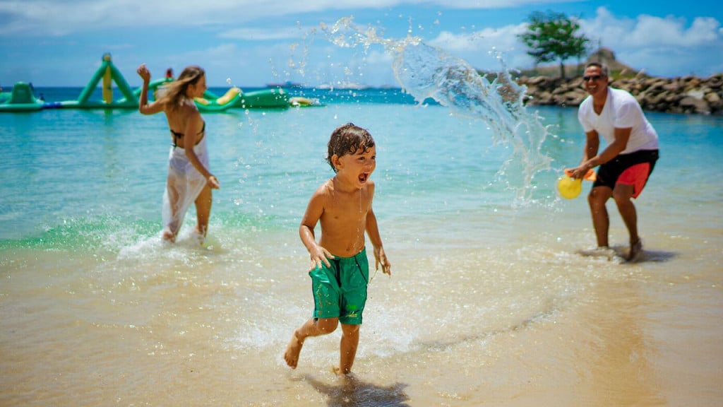 kid splashing with parents on the beach