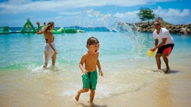 kid splashing with parents on the beach
