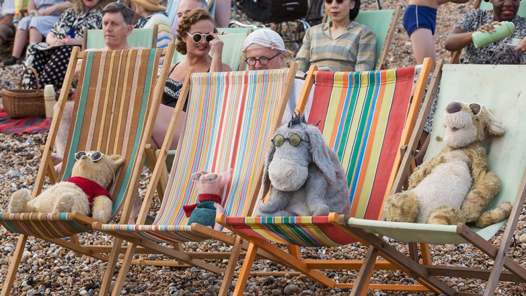 Promo image for Disney's Christopher Robin showing winnie the pooh and friends lounging on beach chairs