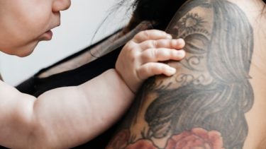 mom holding baby with tattooed arms