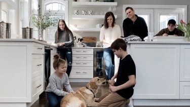 Mom and dad with kids and family dog in kitchen