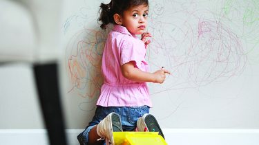 Young girl drawing on wall