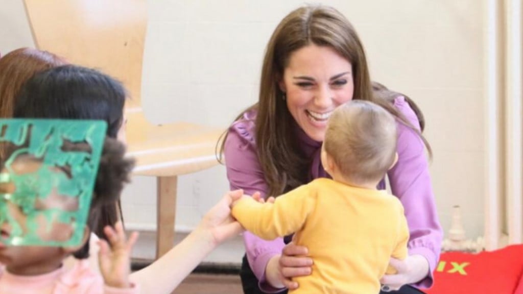 Kate Middleton playing with a toddler in a yellow top