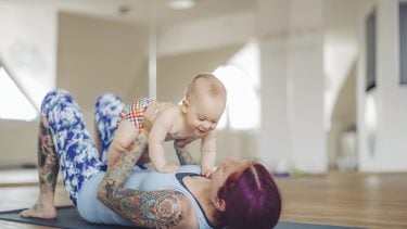 Mother feeding her little daughter at yoga class