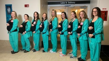 Line of nine nurses who are all pregnant