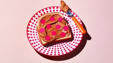 Peanut butter toast with red spots on red dotted white plate with knife