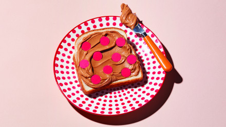 Peanut butter toast with red spots on red dotted white plate with knife