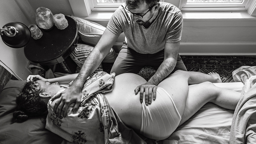 man helping his wife through a home birth