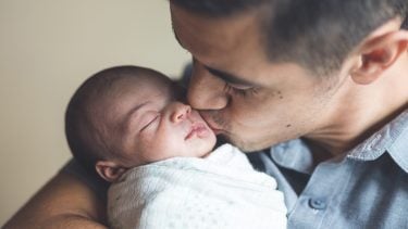 Father kissing newborn baby on the cheek