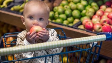 baby eating apple in grocery cart